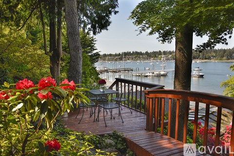 A deck with a table and chairs overlooks a body of water with boats.