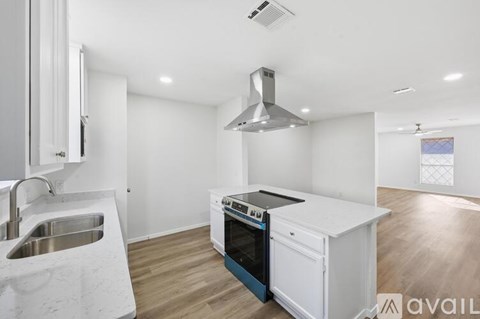 A modern kitchen with white cabinets and a stainless steel sink.