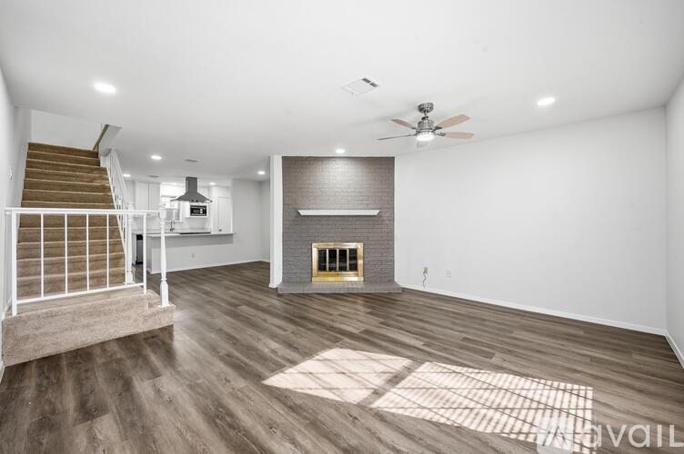 A spacious living room with a fireplace and a staircase.