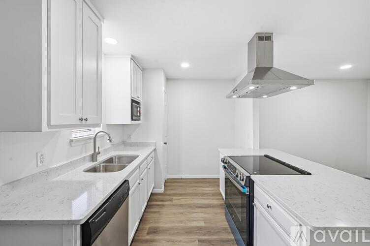 A modern kitchen with white cabinets and a marble countertop.