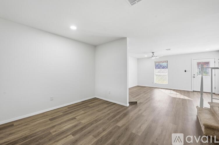 A spacious room with wooden flooring and white walls.