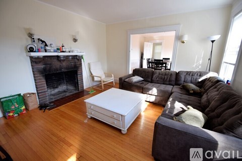 A living room with a fireplace and a grey couch.