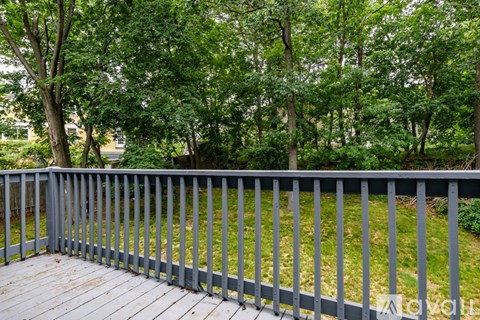 A deck with a metal railing overlooking a grassy area with trees.