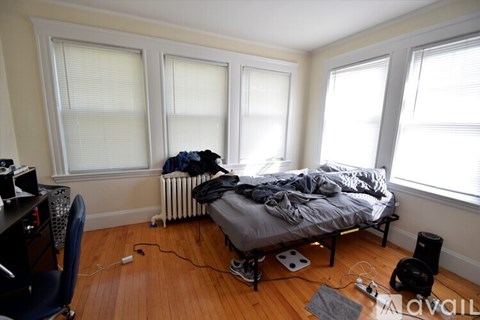 A bedroom with a bed, chair, and a radiator.