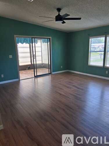A room with a ceiling fan and sliding glass doors.