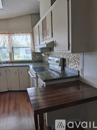 A kitchen with a wooden counter top and white cabinets.