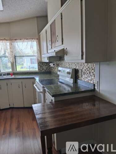 A kitchen with a wooden counter top and white cabinets.