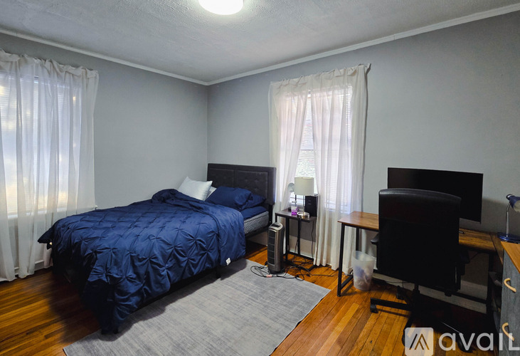 A bedroom with a blue bedspread and a black desk with a computer.