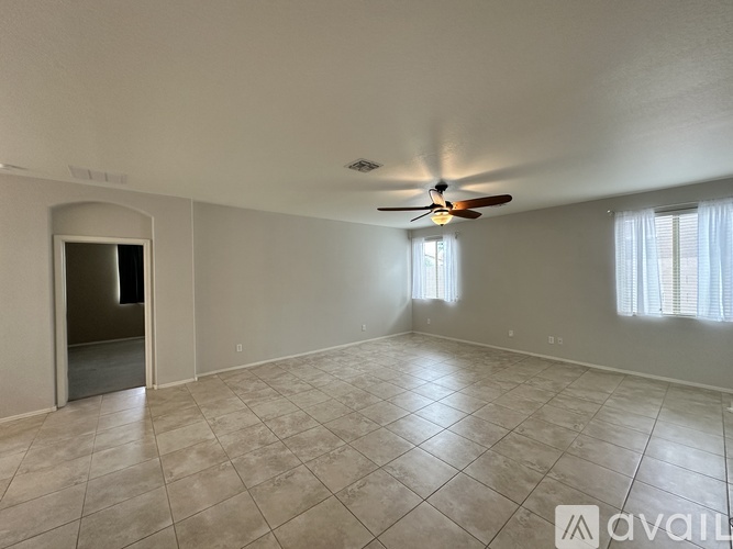 A spacious room with a ceiling fan and tiled flooring.