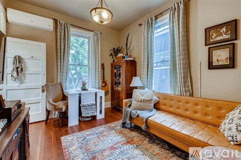 A living room with a brown leather couch and a wooden cabinet.