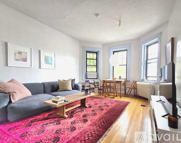 A living room with a grey couch, a wooden coffee table, and a red rug.