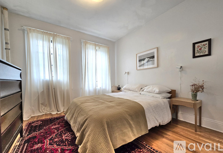 A bedroom with a bed, a bench, and a rug.
