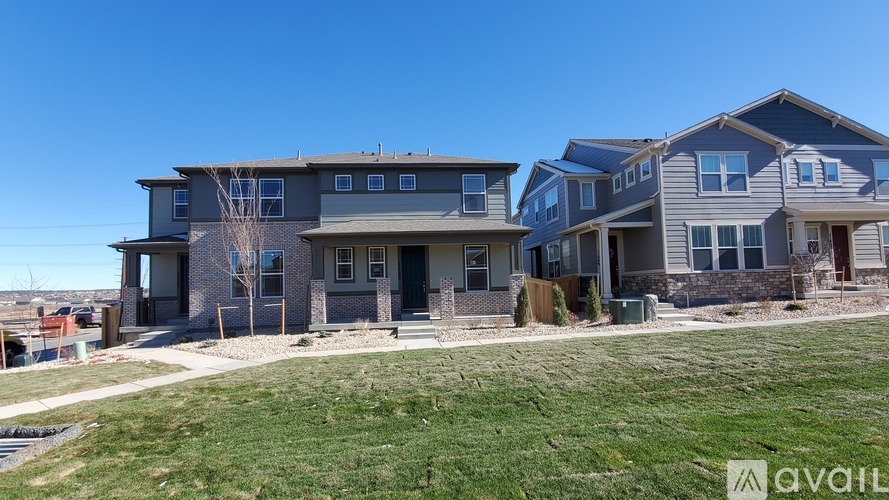 A row of houses with a grassy front yard and a clear blue sky.