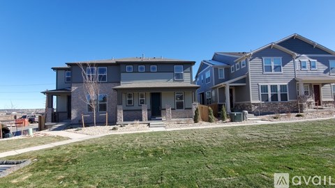 A row of houses with a grassy front yard and a clear blue sky.