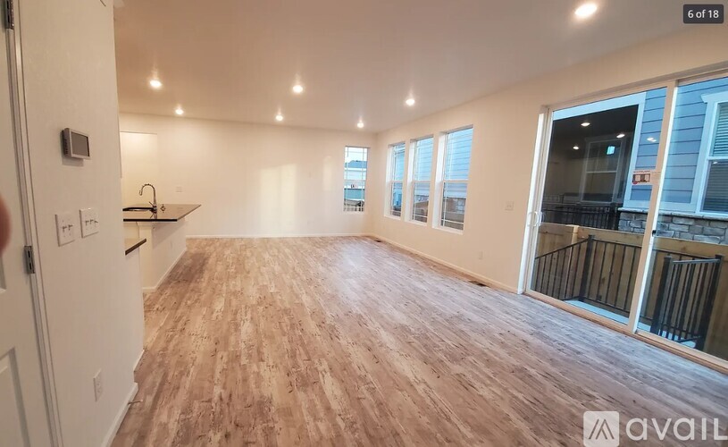 A spacious room with wooden flooring and a balcony with a railing.