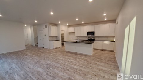 A spacious kitchen with white cabinets and a wooden floor.