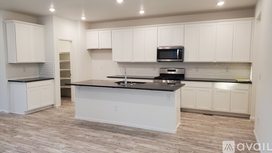 A kitchen with white cabinets and a black countertop.