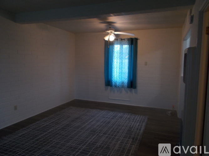 A room with a ceiling fan and a window with blue curtains.