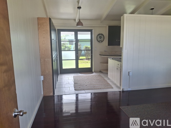 A hallway with a door on the left and a kitchen area on the right.