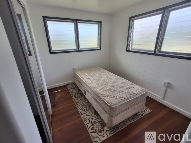 A bedroom with a bed and a rug in the middle of the room.
