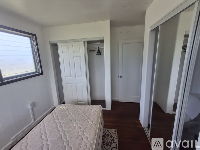 A bedroom with a bed, a window, and a door.