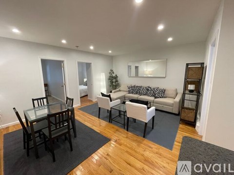 A living room with a glass table and chairs, a couch, and a small Christmas tree.