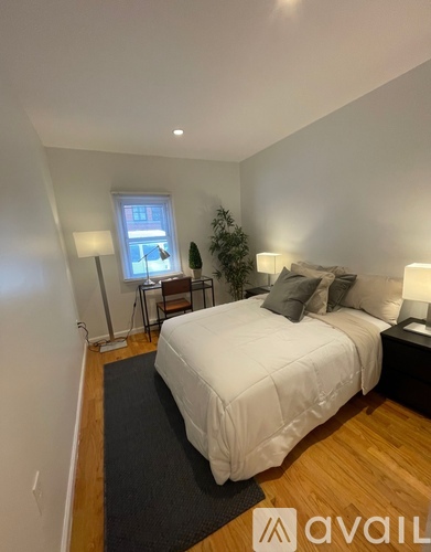A bedroom with a large bed and a small table with a lamp.