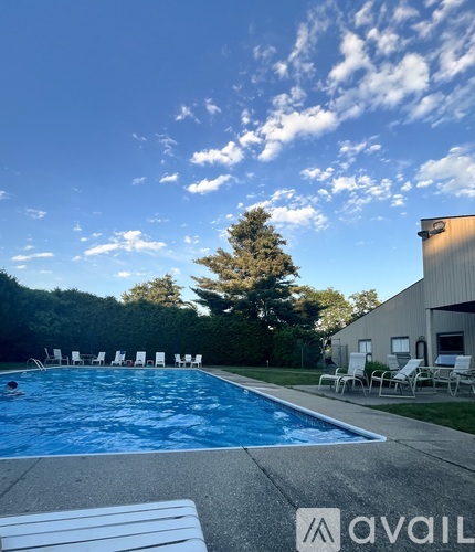 A pool with chairs around it and a building in the background.