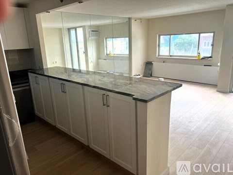 A kitchen with white cabinets and a black countertop.