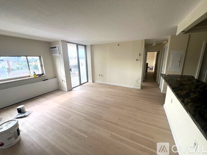 A spacious room with wooden flooring and a large window.
