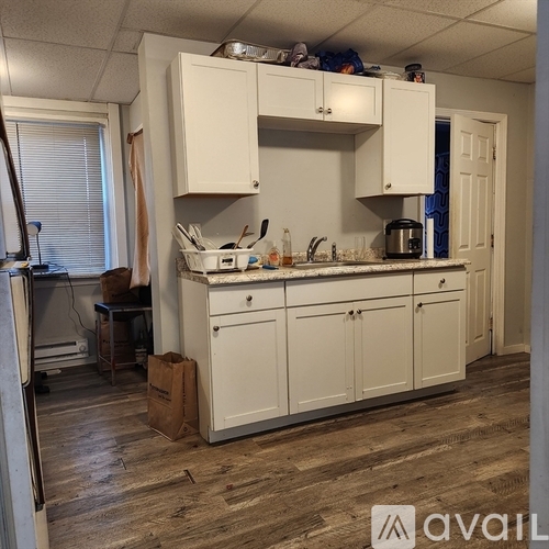 A kitchen with white cabinets and wooden floors.