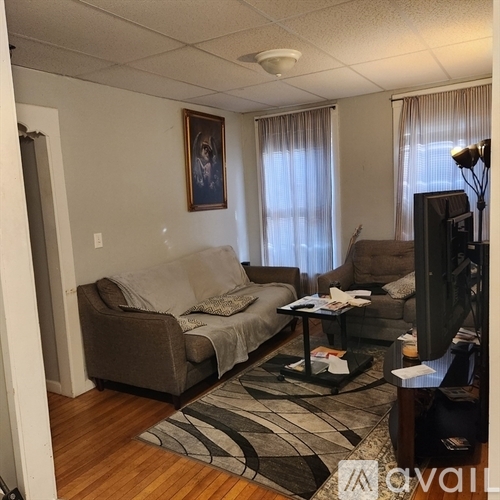 A living room with a grey couch, a black coffee table, and a painting on the wall.