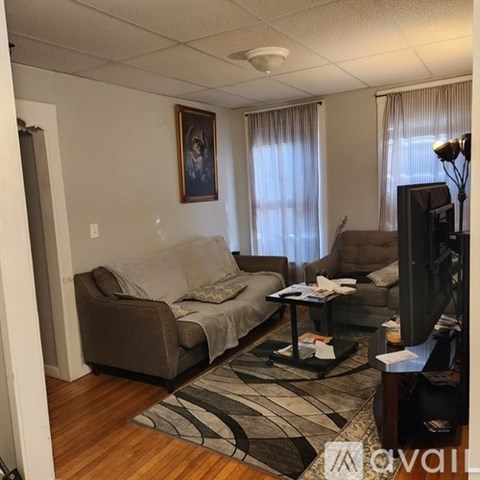A living room with a grey couch, a black coffee table, and a painting on the wall.