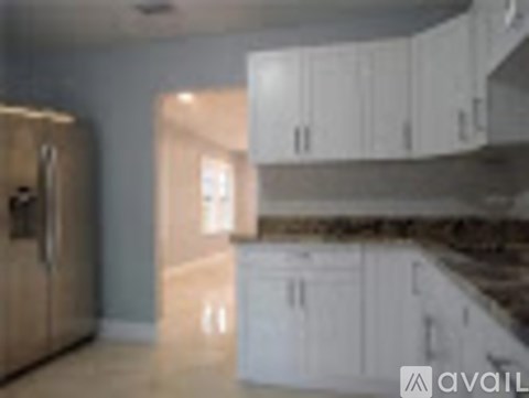 A kitchen with white cabinets and a wooden floor.