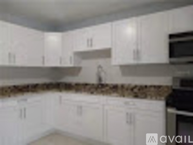 A kitchen with white cabinets and a stone backsplash.