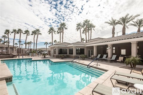 A pool surrounded by palm trees and lounge chairs.