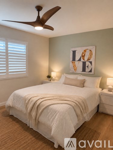 A bedroom with a bed, a ceiling fan, and a "LOVE" sign on the wall.