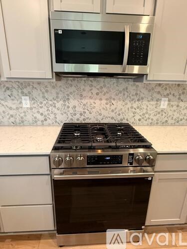 A modern kitchen with a stove top oven and microwave above it.