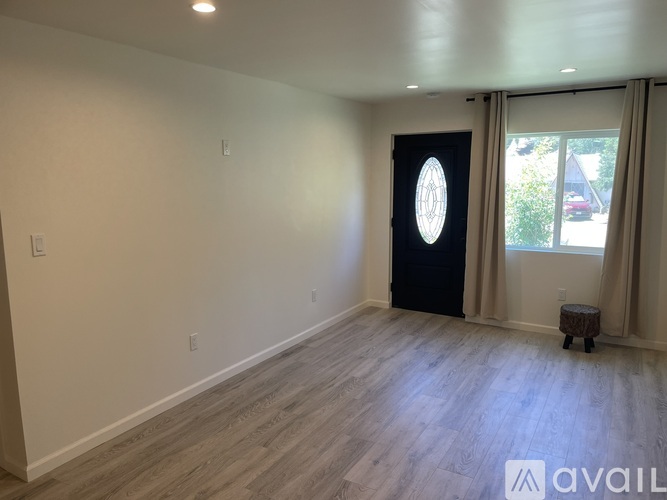 A room with a black door and a window with beige curtains.