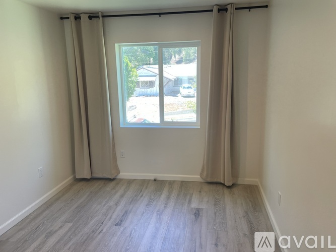A room with a large window and beige curtains.