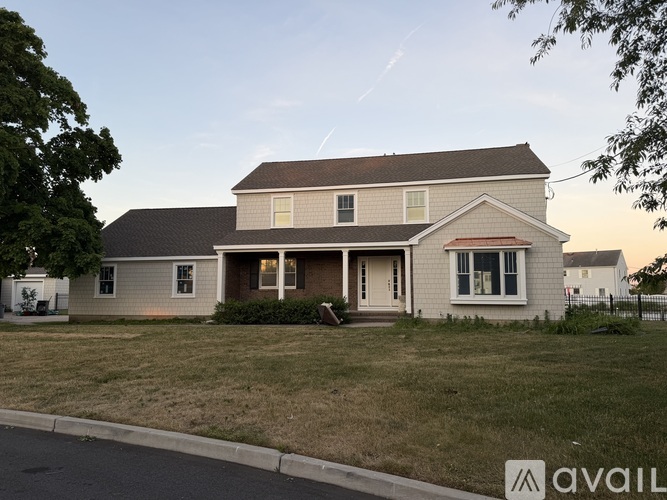 A house with a front yard and a tree on the left.