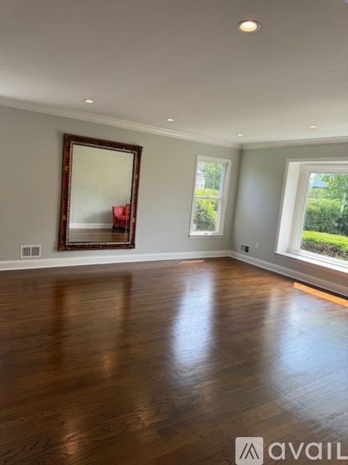 A spacious room with wooden floors and a large mirror on the wall.