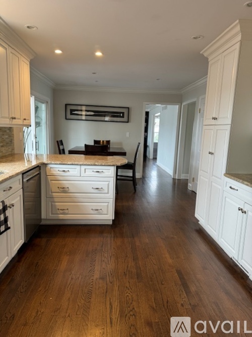 A kitchen with white cabinets and a wooden floor.
