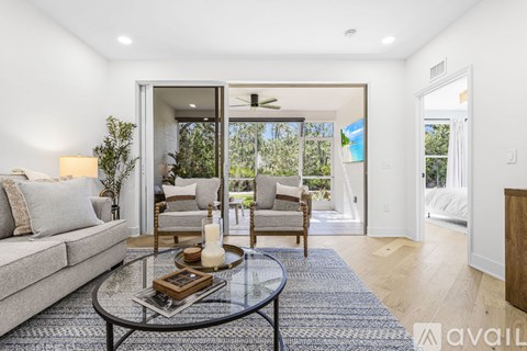 A modern living room with a glass coffee table and a grey sofa.
