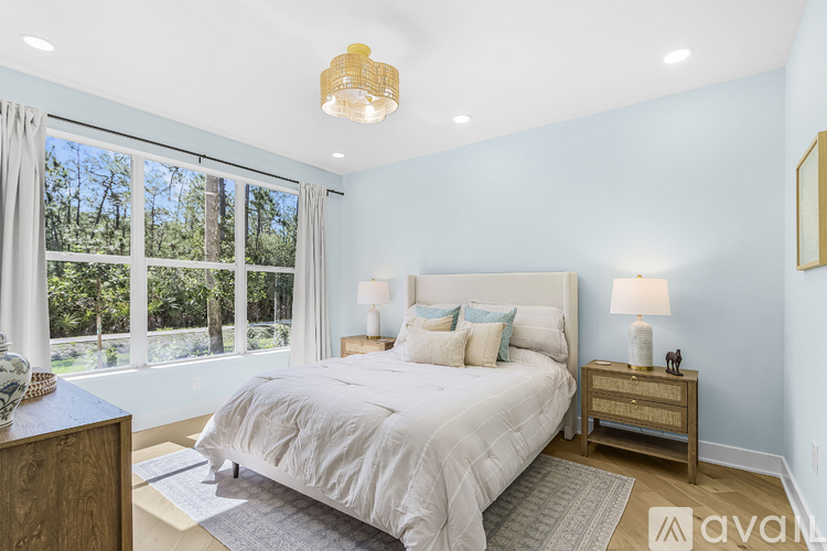 A bedroom with a large bed and a window overlooking a forest.