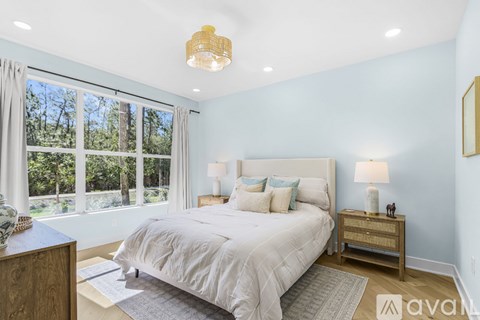 A bedroom with a large bed and a window overlooking a forest.