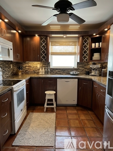 A kitchen with a fan and brown tiles.