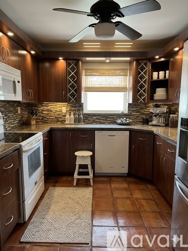 A kitchen with a fan and brown tiles.