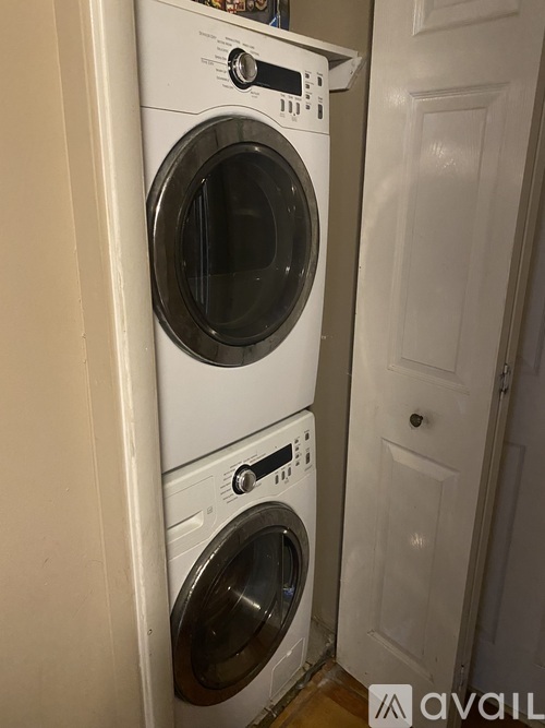 A white washing machine and dryer stacked on top of each other in a small room.