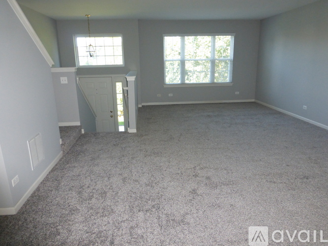 A spacious room with a carpeted floor and a staircase leading to the upper level.